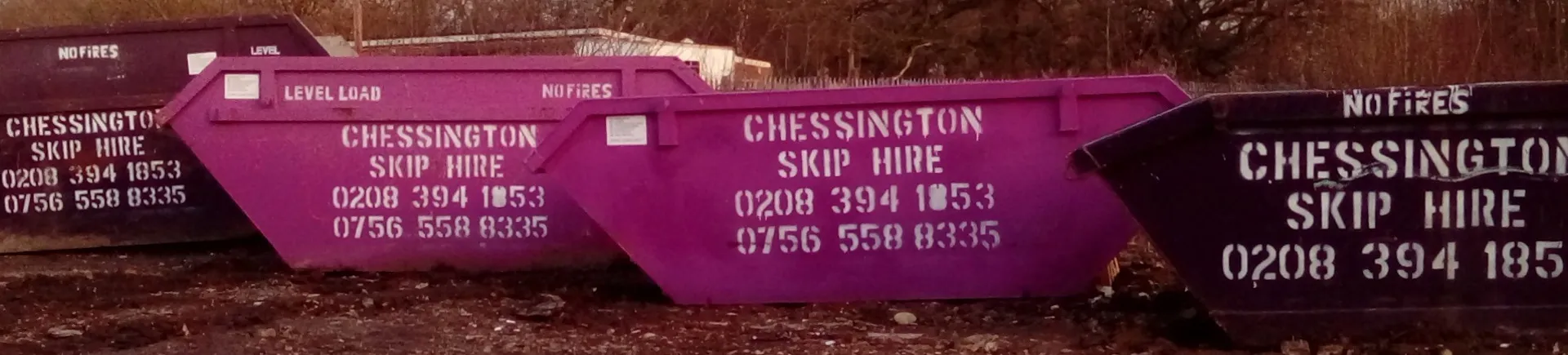 Chessington Skip Hire skips, painted with the company name and phone numbers