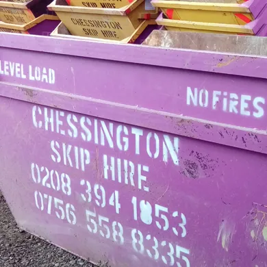 A magenta Chessington Skip Hire skip